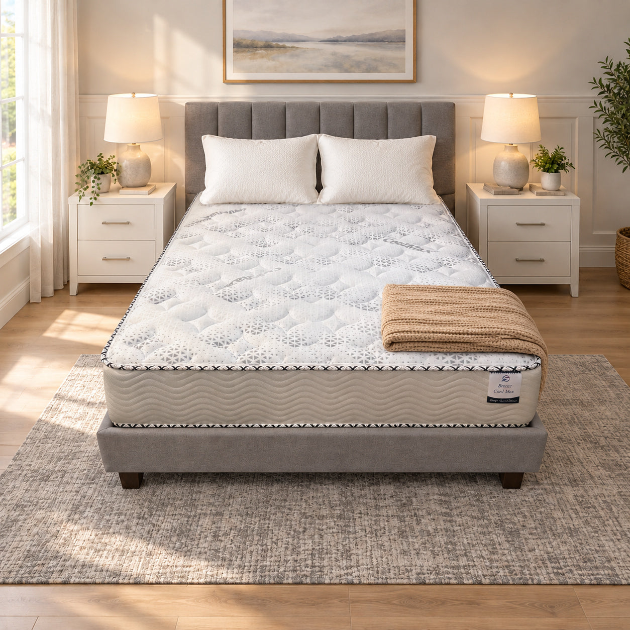 Double Full XL Breeze Cool Max 10" Medium Firm Tight top mattress on a gray upholstered bed with two white pillows and a tan knit throw, in a bedroom with white nightstands, table lamps and a framed landscape print