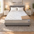 Olympic Queen Breeze Cool Max 10" Medium Firm Tight top mattress on a gray upholstered bed with two white pillows and a tan knit throw, in a bedroom with white nightstands, table lamps and a framed landscape print